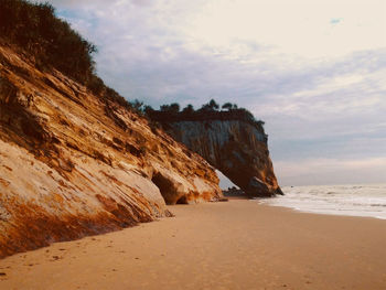 Rock formations on beach against sky