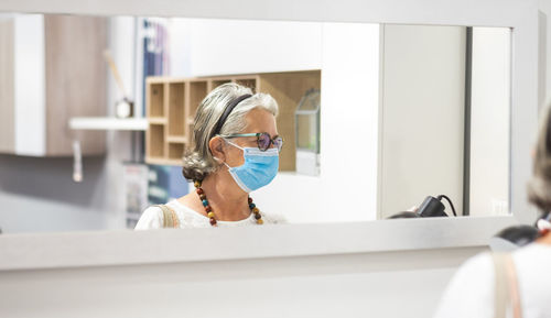 Woman wearing mask reflecting in mirror