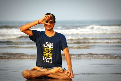 Full length of wet young man practicing yoga at beach