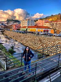 Portrait of man standing by railing against buildings in city