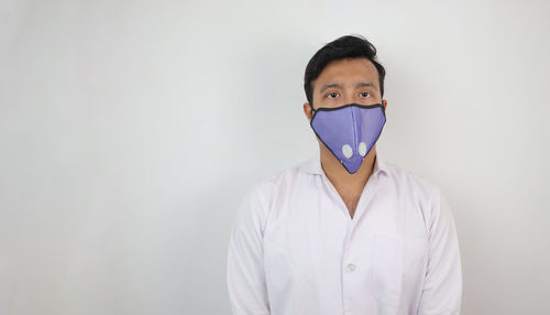 Portrait of young man standing against white background