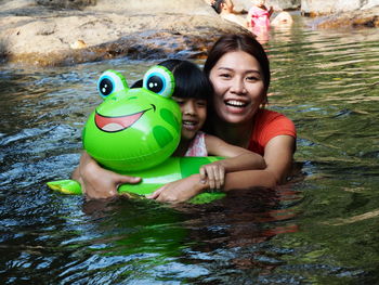 Portrait of smiling young woman with toy floating in water