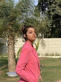 Side view of young woman standing against trees