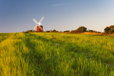 Traditional windmill on land against sky at sunset