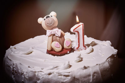 Close-up of burning candle with bear figurine on cake