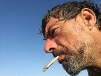 Close-up of man smoking against sky