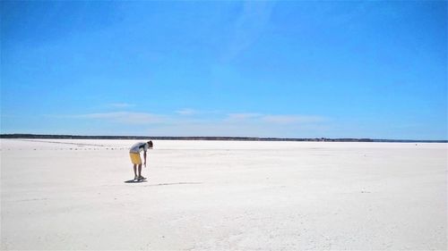 Rear view of man on beach against clear blue sky