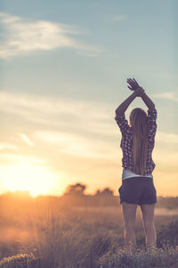 Rear view of woman standing on field against sky