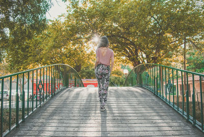 Rear view of woman walking on footbridge