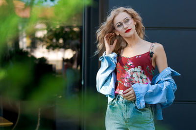 Beautiful blonde woman wearing glasses and wearing blue denim and jeans posing on street in city