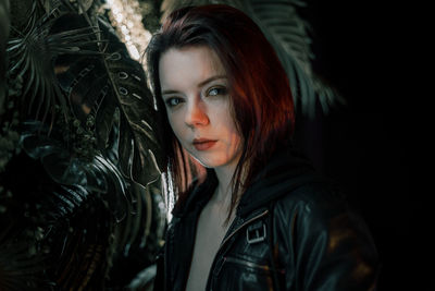 Portrait of young woman standing against black background