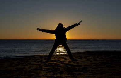 Man in sea against sky during sunset
