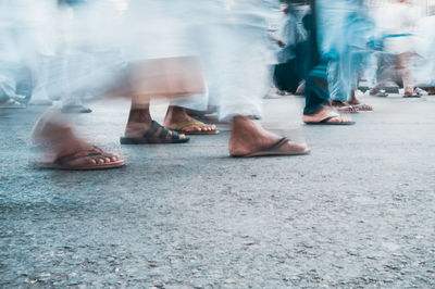 Low section of people walking on street in city