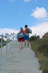 Rear view of friends on shore against sky