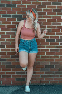 Full length of woman standing against brick wall