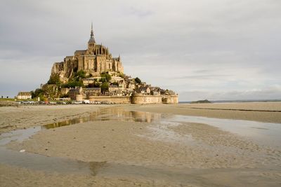 Building at beach against cloudy sky