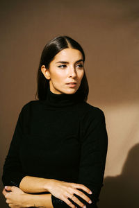 Portrait of young woman standing against wall