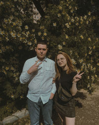 Full length of young couple standing against tree