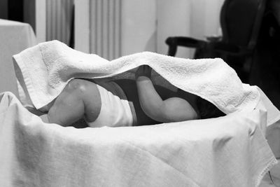 Baby covered with towel resting on crib