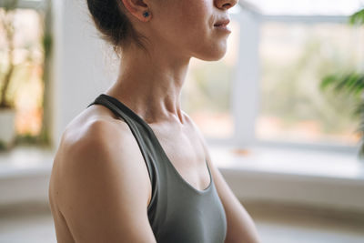 Crop photo of young fit woman practice yoga doing asana in light yoga studio with green house plant