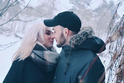 Young couple kissing in forest during winter