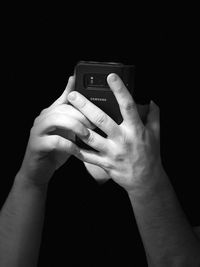 Close-up of hand holding smart phone against black background