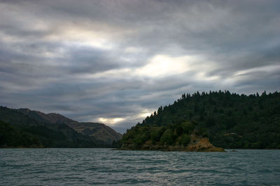 Scenic view of sea and mountains against cloudy sky