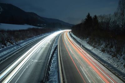 Light trails on road against sky at night