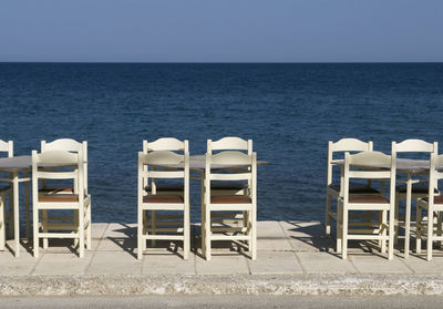 Chairs on beach against clear sky