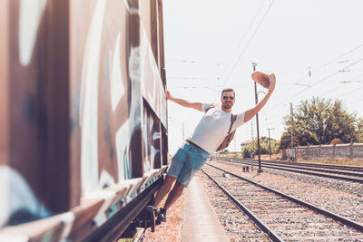 Full length of man hanging on train against sky