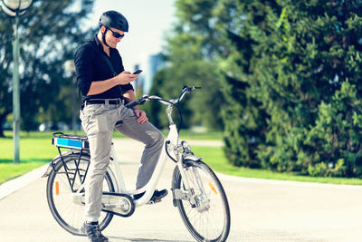 Businessman using mobile phone while sitting on bicycle