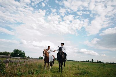 Couple riding horse on field