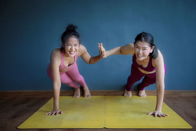 Portrait of smiling women exercising against wall
