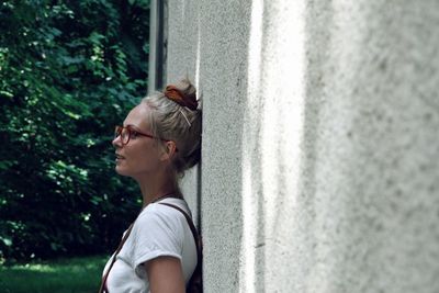 Side view of thoughtful woman looking away while leaning on wall