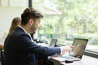 Businessman using laptop while sitting at desk in office