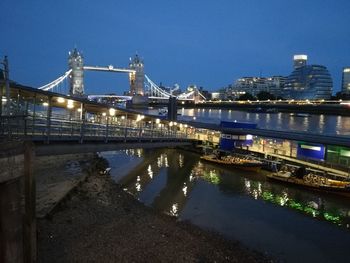 Illuminated bridge over river against sky at night