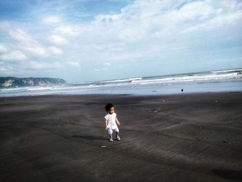 Rear view of girl on beach against sky