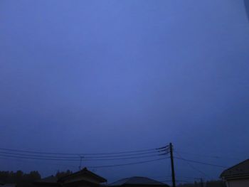 Low angle view of electricity pylon against blue sky