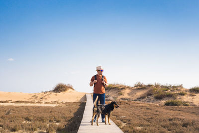 Man with dog on street against sky