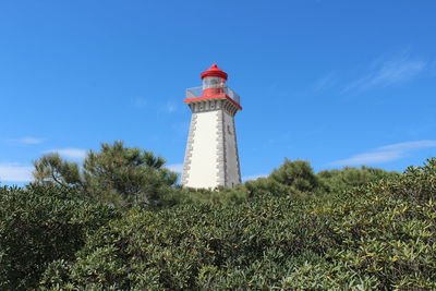 Low angle view of lighthouse by building against sky