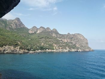 Scenic view of rocky mountain by sea against sky