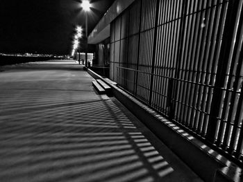 Shadow of railing on illuminated walkway at night