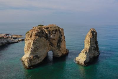 Rock formation in sea against sky