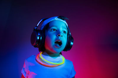 Cyberpunk boy child in a white t shirt and large headphones listening to music on the background 