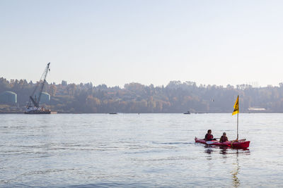 People on boat in sea against clear sky