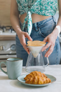 Midsection of woman holding coffee cup on table