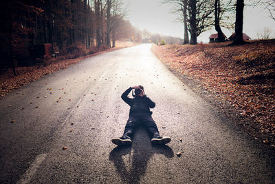 High angle view of man photographing while lying on road