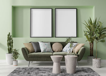 Two empty vertical picture frames on green wall in modern living room. mock up interior 