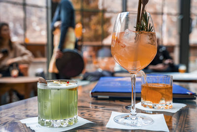 Orange and green colored drinks in glasses on table at restaurant in resort