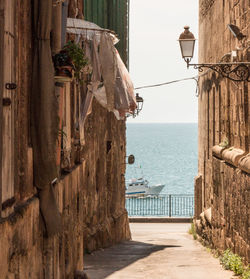 Narrow alley amidst sea against sky